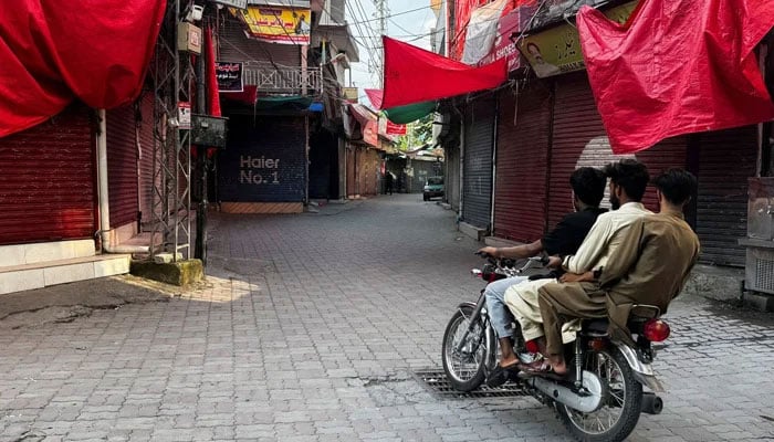 Men ride on a motorbike along a deserted market. — Reuters/File