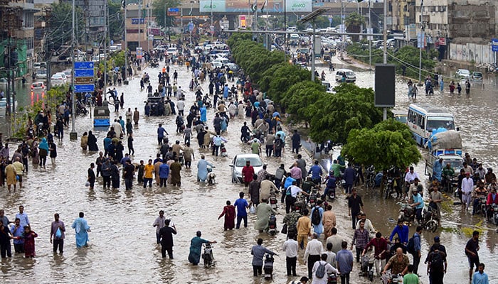 People wade through a flooded road after the monsoon rain in Karachi, Pakistan, August 19, 2025. — Reuters