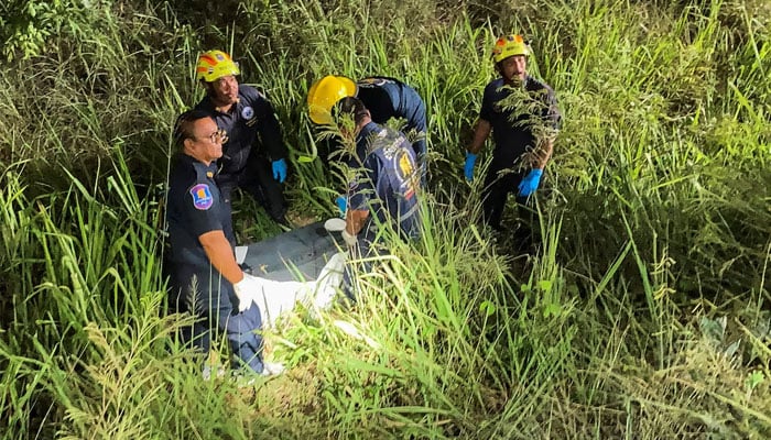 Rescue workers recover a suitcase from a grassy area near a railway track, in which police later found the body of a 17-year-old Thai girl, in Pattaya City, Thailand, June 27, 2026.—Reuters