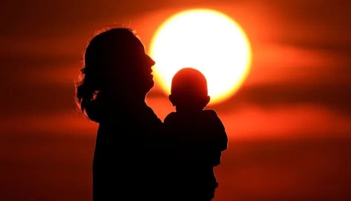 A mother and her baby enjoy the sunset on the beach in Calais, France, August 16, 2023. — Reuters