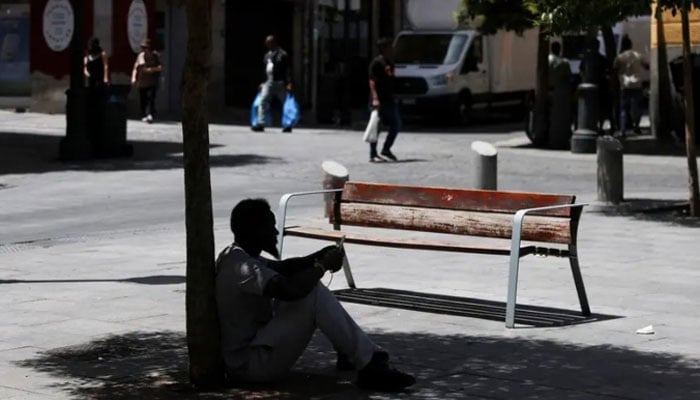 A man sits in the shade of a tree to escape the heat during a heatwave in Madrid, Spain, June 23, 2026. — Reuters