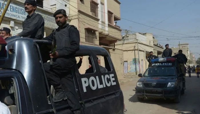 Sindh Police personnel can be seen passing on a police vehicle in Karachi. —AFP/File