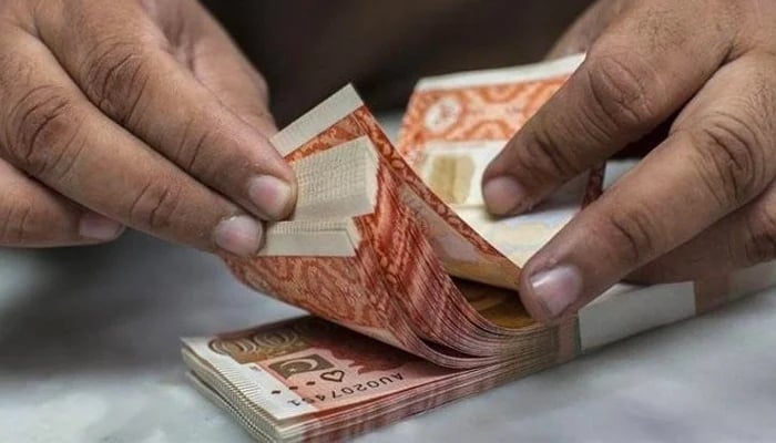 A money changer counts Rs5,000 notes. — AFP/File