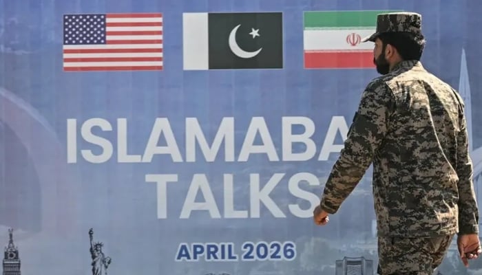 A Pakistani Ranger walks past a billboard for the US-Iran peace talks in Islamabad on April 12, 2026. — AFP