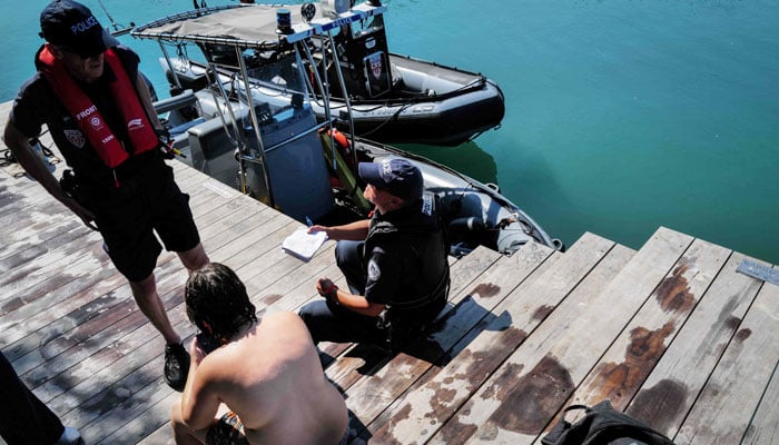 French National police and the river brigade control a group of teenagers who were jumping off the Passerelle de la Paix bridge into the Rhône River, in Lyon, southern France, on June 25, 2026, during a heatwave in France and Europe. — AFP