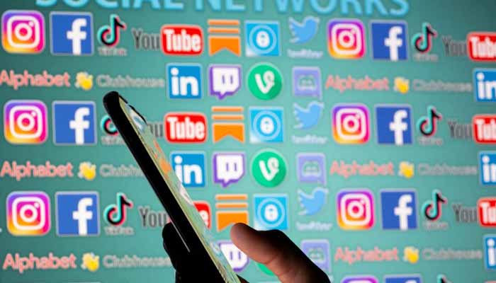 A woman with a smartphone is seen in front of displayed social media logos in this illustration taken, May 25, 2021. — Reuters