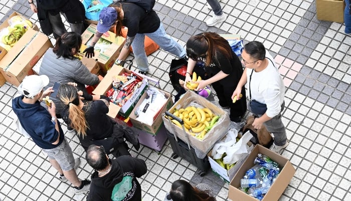 Volunteers give out food and drinks after a major fire swept through several apartment blocks at the Wang Fuk Court residential estate in Hong Kongs Tai Po district on November 27, 2025. — AFP