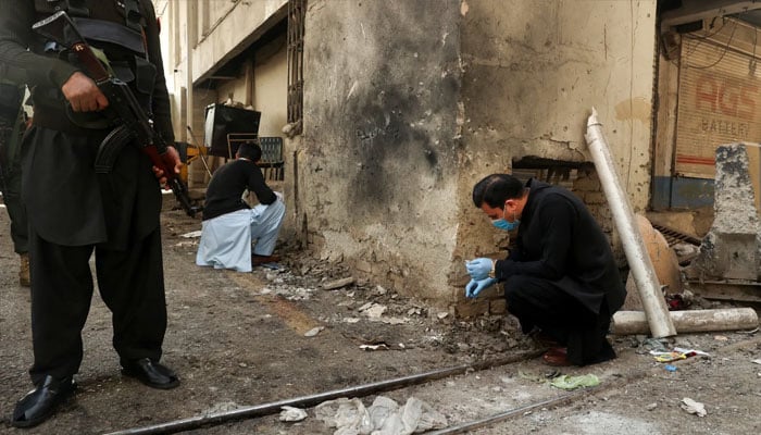Members of the forensic team collect evidence from a site after suicide bombers targeted the Federal Constabulary headquarters in Peshawar on November 24. — Reuters