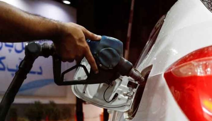 A worker holds a fuel nozzle to fill fuel in a car at petrol station in Karachi. — Reuters/File