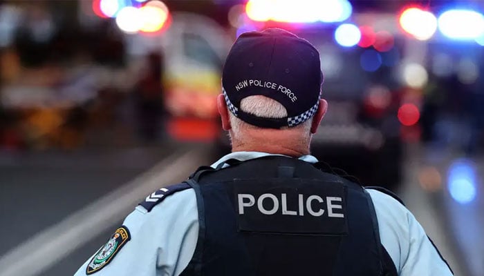 A member of the New South Wales Police Force is seen from the backside at a crime scene. — AFP