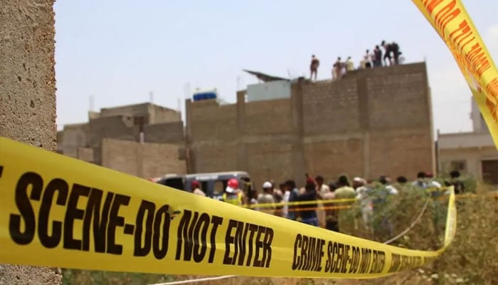 Representational image of residents gathered at a crime scene as police personnel inspect a site cordoned off with barricade tapes in Karachi on May 8, 2025. — Reuters