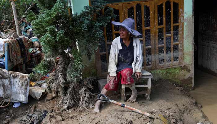 Survivor Rismawati Simanjuntak, 63, sits as she takes a break while collecting valuable goods and cleaning her house following deadly flash flood in Batang Toru, South Tapanuli, North Sumatra province, Indonesia, December 6, 2025.— Reuters