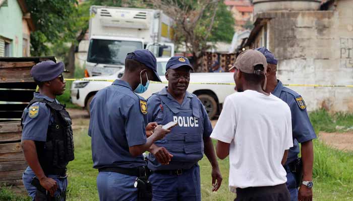 Police speak to a resident at the scene where several people, including three minors, were killed in a mass shooting in Saulsville Hostel in Atteridgeville in Pretoria, South Africa, December 6, 2025.— Reuters