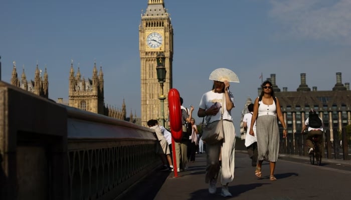 A woman shields her face from the sun as she crosses Westminster Bridge during a heatwave, in London, Britain, August 12, 2025. — Rueters