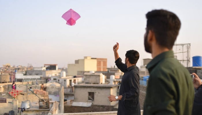 Youths fly kites on a rooftop during the Basant festival in Rawalpindi, February 18, 2022. — AFP