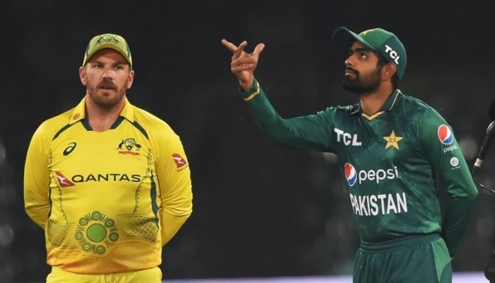 Pakistans Babar Azam (right) tosses the coin as his Australian counterpart Aaron Finch watches before the start of the Twenty20 international cricket match between Pakistan and Australia at the Gaddafi Cricket Stadium in Lahore on April 5, 2022. — AFP