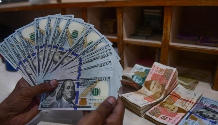 A foreign currency dealer counts US dollars at a shop in Karachi. — AFP/File