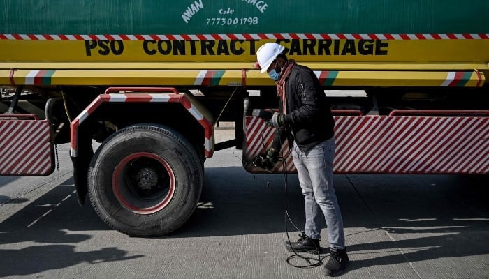 This picture taken on December 10, 2025, shows technician Waleed Ahmed examining a vehicle to test its emissions on road, on the outskirts of Islamabad. — AFP