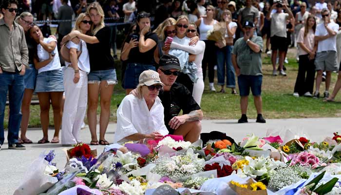 Mourners gather by floral tributes at the Bondi Pavillion in memory of the victims of a shooting at Bondi Beach, in Sydney on December 15, 2025. — AFP