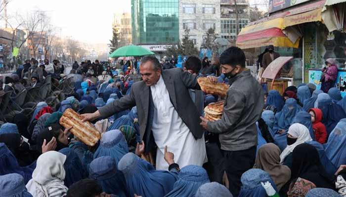 A bakery in charge distributes bread among the needy in front of the bakery in Kabul, Afghanistan. — Reuters