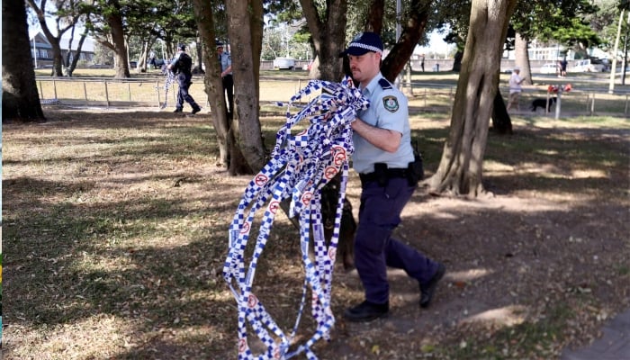 Police officers remove police tape from the scene of Sunday’s shooting at Bondi Beach, in Sydney on December 17, 2025. — AFP