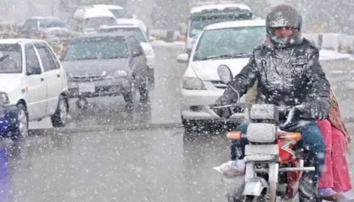 Commuters travel during light snow in Punjab. — AFP/File