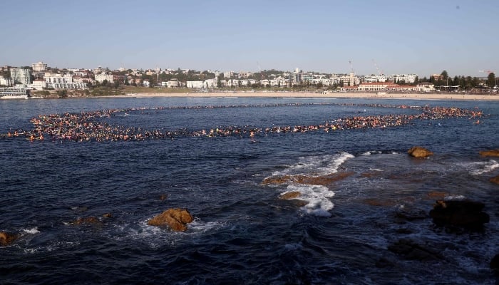 Surfers and swimmers form a circle in the surf at Bondi Beach as they participate in a tribute for the victims of Sundays Bondi Beach attack, in Sydney on December 19, 2025. — AFP