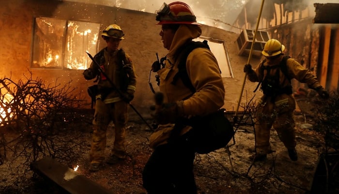 Cal Fire firefighters try to save a burning structure in Paradise, California, US. — Reuters