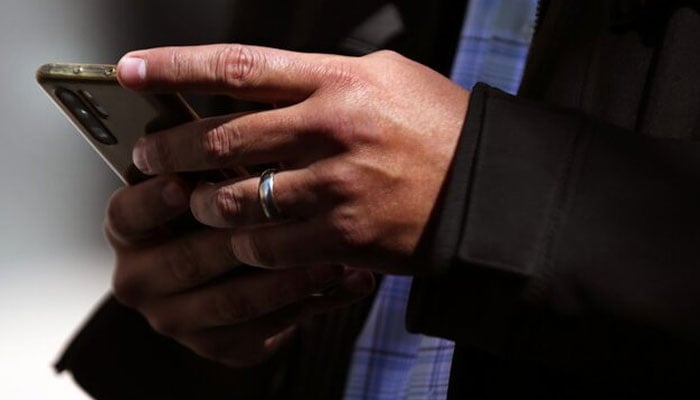 This representational image shows a man holds his mobile phone in downtown Mexico City, Mexico, February 3, 2021. — Reuters