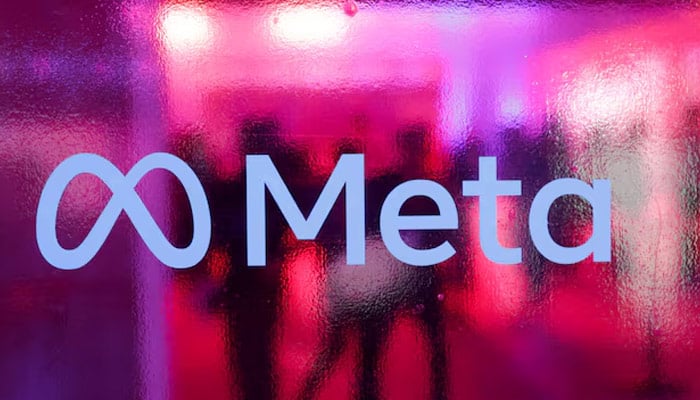 People walk behind a logo of Meta Platforms company, during a conference in Mumbai, India, September 20, 2023. — Reuters