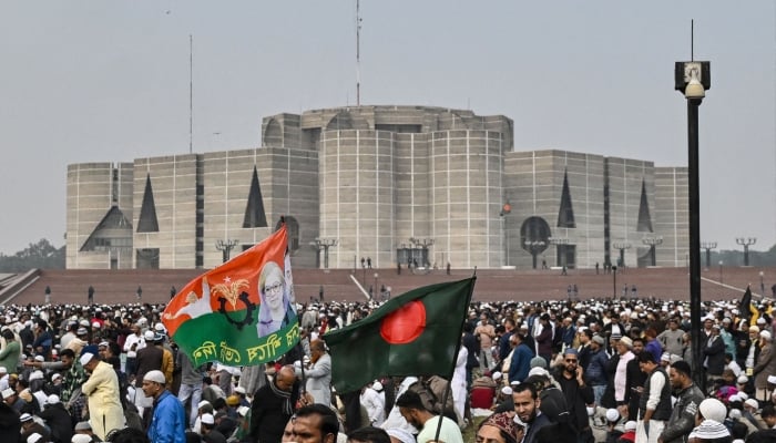 Mourners hold flags with a portrait of Bangladeshs former prime minister Khaleda Zia along with the country´s national flag during her funeral ceremony at the Parliament House premises in Dhaka, December 31, 2025. — AFP