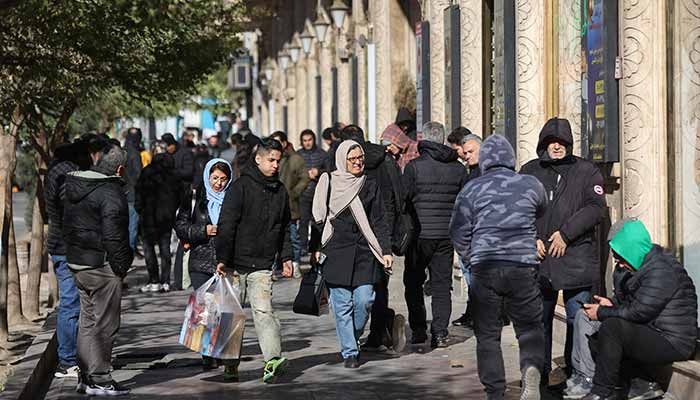 People walk past stores as the value of the Iranian Rial drops, in Tehran, Iran, December 30, 2025. — Reuters