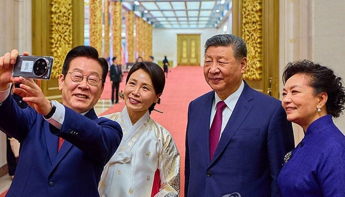 President Lee Jae Myung (left) takes a selfie with first lady Kim Hea Kyung (2nd from left), along with Chinese President Xi Jinping (2nd from right) and his wife, Peng Liyuan (right), after a state dinner at the Great Hall of the People in Beijing on Jan. 5, 2026. — Yonap/File