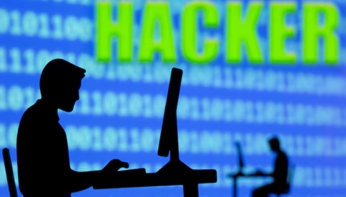 A 3D printed model of men working on computers are seen in front of displayed binary code and words Hacker in this illustration taken, July 5, 2021. — Reuters