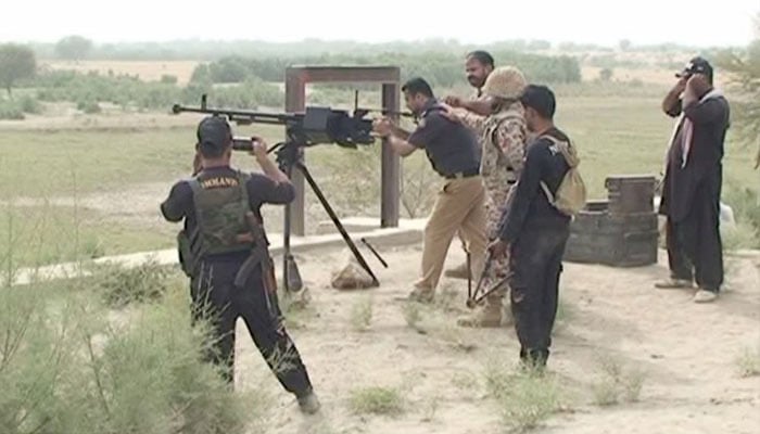 A policeman fires a heavy machine gun towards bandits holed up in katcha area of Kashmor district. — Geo News screengrab/File
