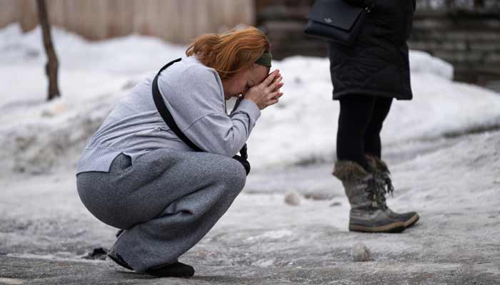 Katie Brown holds her hands to her face at a memorial for Renee Nicole Good near the site of her shooting on January 08, 2026 in Minneapolis. — AFP