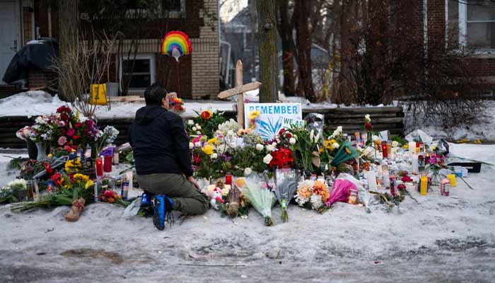 A man kneels at a memorial for Renee Nicole Good near the site of her shooting on January 08, 2026 in Minneapolis. — AFP