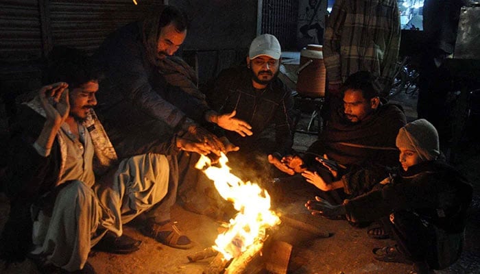 People warm their hands on bone-fire to save themselves from cold waves during the winter season, in Hyderabad on Sunday, December 22, 2024. — APP