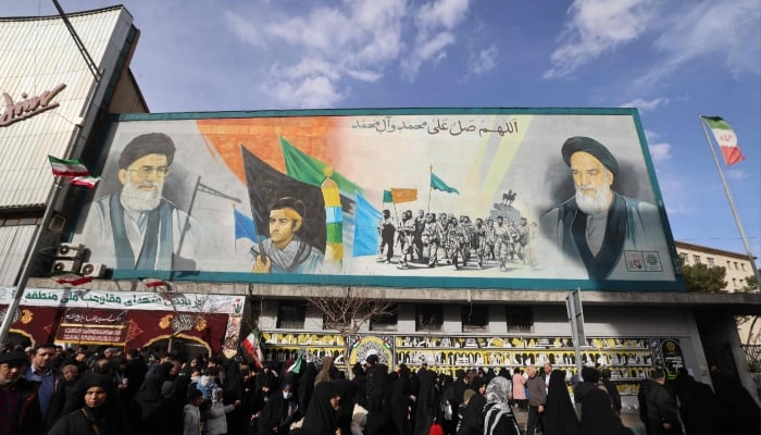 People walk past a banner depicting Iran’s Supreme Leader Ayatollah Ali Khamenei and late leader Ruhollah Khomeini on Enghelab (Revolution) Square in Terhan, January 14, 2026. — AFP