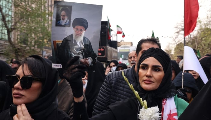 An Iranian woman holds a portrait of Iran’s Supreme Leader Ayatollah Ali Khamenei during the funerals of security forces personnel killed in recent protests in Tehran, January 14, 2026. — AFP