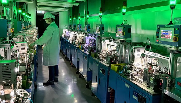 The image depicts a worker in a cleanroom environment operating machinery at a semiconductor manufacturing facility in Taiwan. — Reuters/File