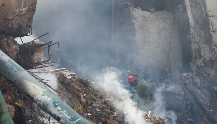 A rescue worker walks amid rubble and smoke to search for survivors at the site, following a massive fire that broke out at the Gul Plaza Shopping Mall, in Karachi, January 21, 2026. — Reuters