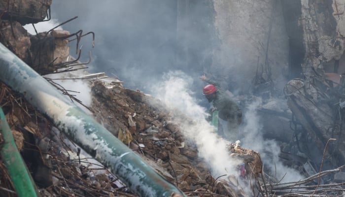 A rescue worker walks amid rubble and smoke to search for survivors at the site, following a massive fire that broke out at Karachi Gul Plaza Shopping Mall, January 21, 2026. — Reuters