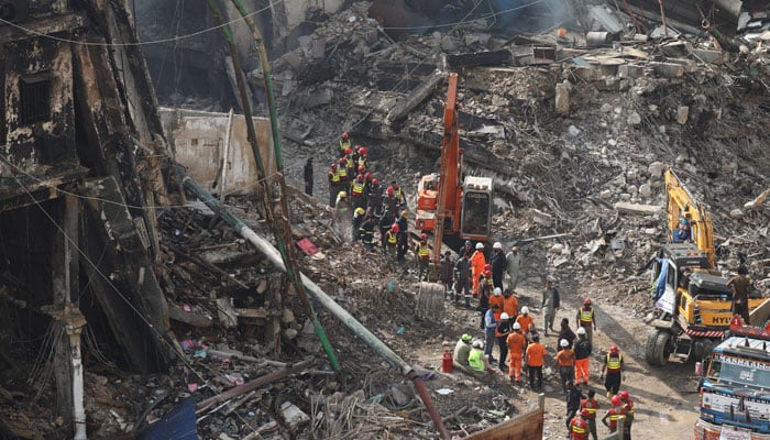 Rescue and emergency team members gather near heavy machinery before starting their search for survivors, following a massive fire that broke out in the Gul Plaza Shopping Mall in Karachi, January 22, 2026. — Reuters