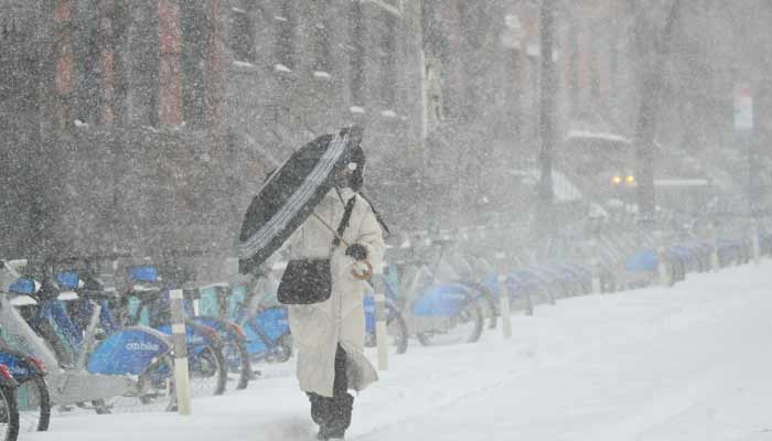A woman carries an umbrella as she walks in the falling snow in New York City on January 25, 2026.— AFP