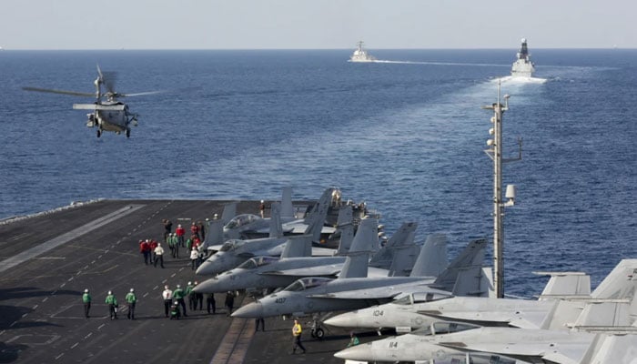 The aircraft carrier USS Abraham Lincoln transits the Strait of Hormuz as a helicopter lifts off from the flight deck, on 19 November 2019. — AFP