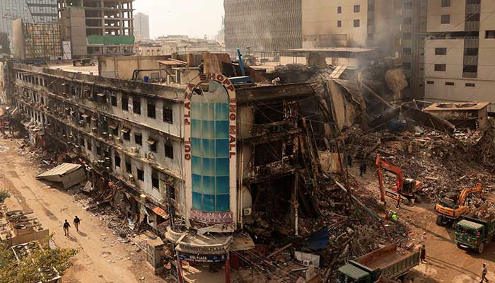 Fire department workers walk past the site, following a massive fire that broke out in the Gul Plaza shopping centre in Karachi on January 20, 2026. — Reuters