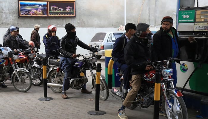 People wait for their turn to get fuel at a petrol station in Peshawar, on January 24, 2023. — Reuters