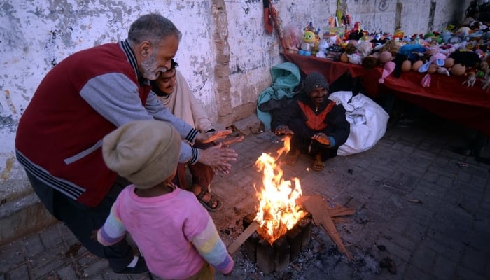 People warm their hands at bonfire to keep themselves safe from cold weather in Safdar, Karachi, on January 23, 2026. — PPI
