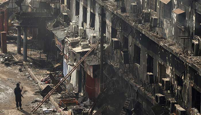 A police officer takes photos of a damaged building with his mobile as he guards the street, following a massive fire that broke out in the Gul Plaza Shopping Mall in Karachi, Pakistan, January 22, 2026. — Reuters